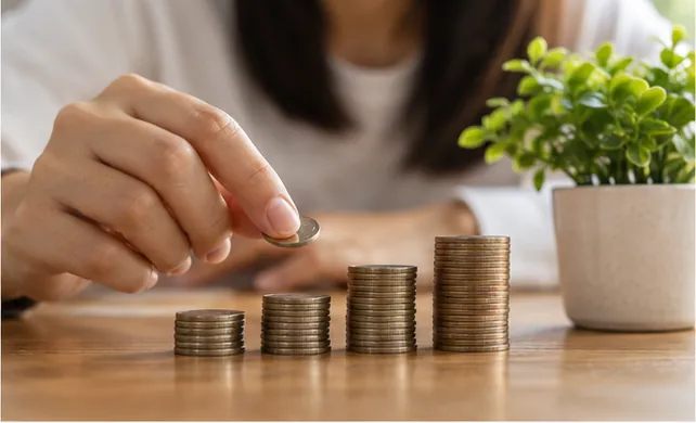 Hands stack coins to show compound interest growth over time